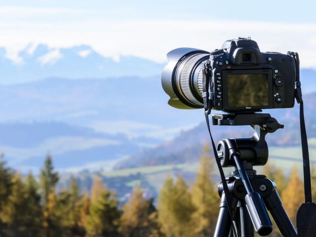 Photographer with a camera on a tripod overlooking mountains